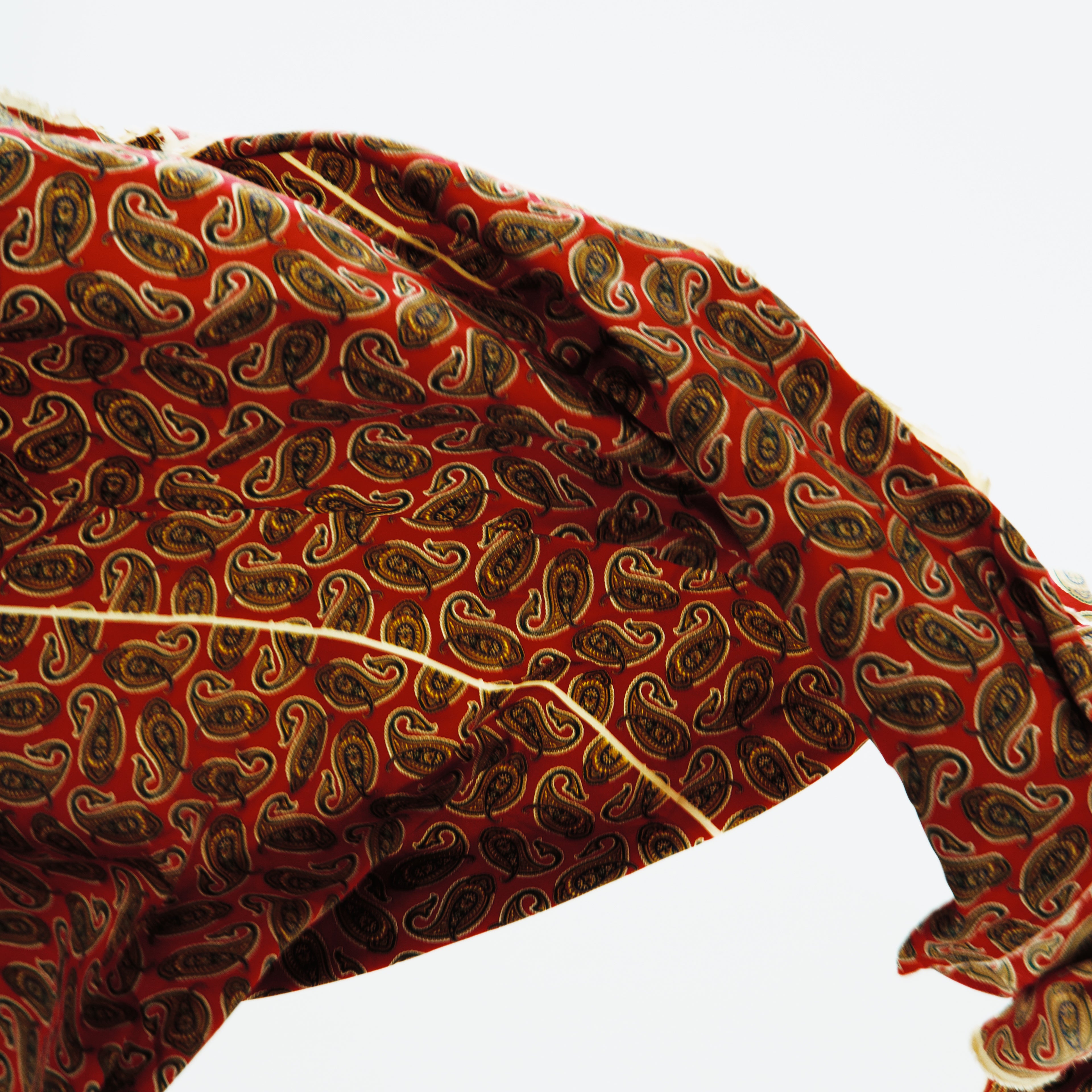 Red fabric with brown paisley pattern on a white background