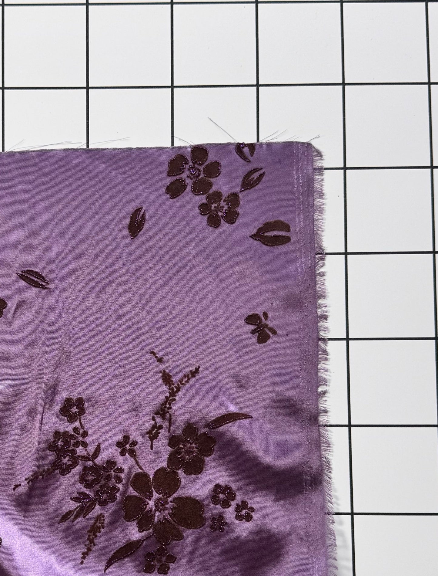 Purple fabric with floral patterns on a grid background