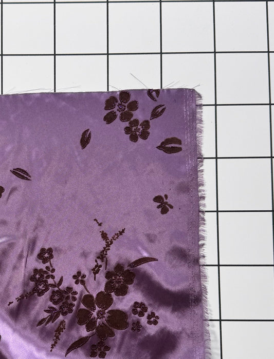 Purple fabric with floral patterns on a grid background