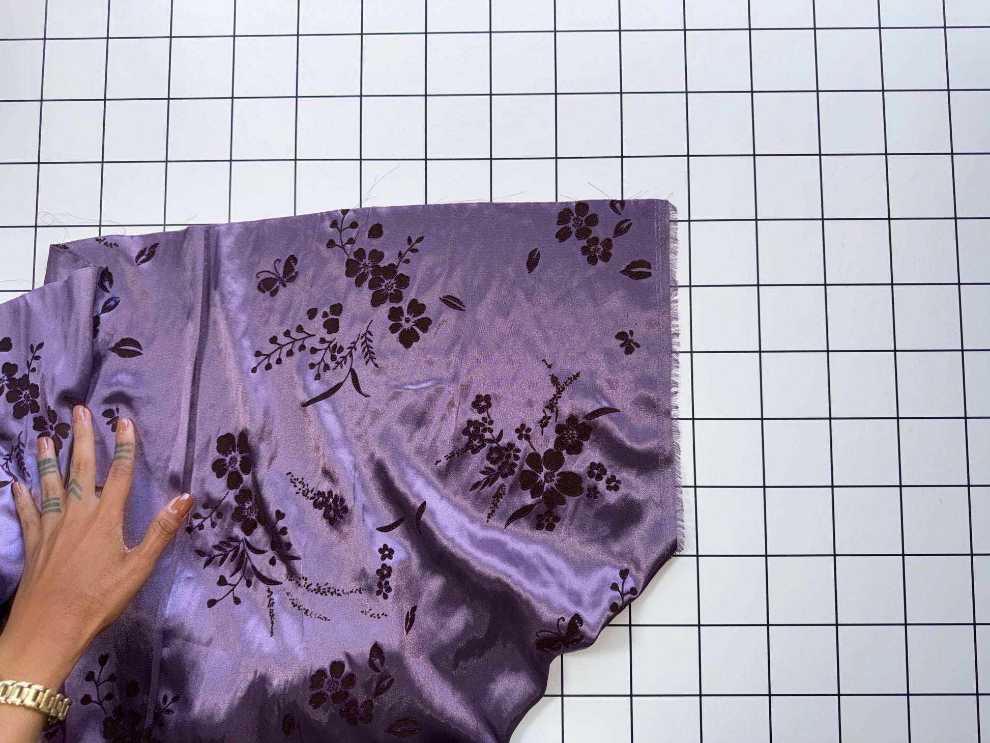 Purple fabric with black floral patterns on a grid background