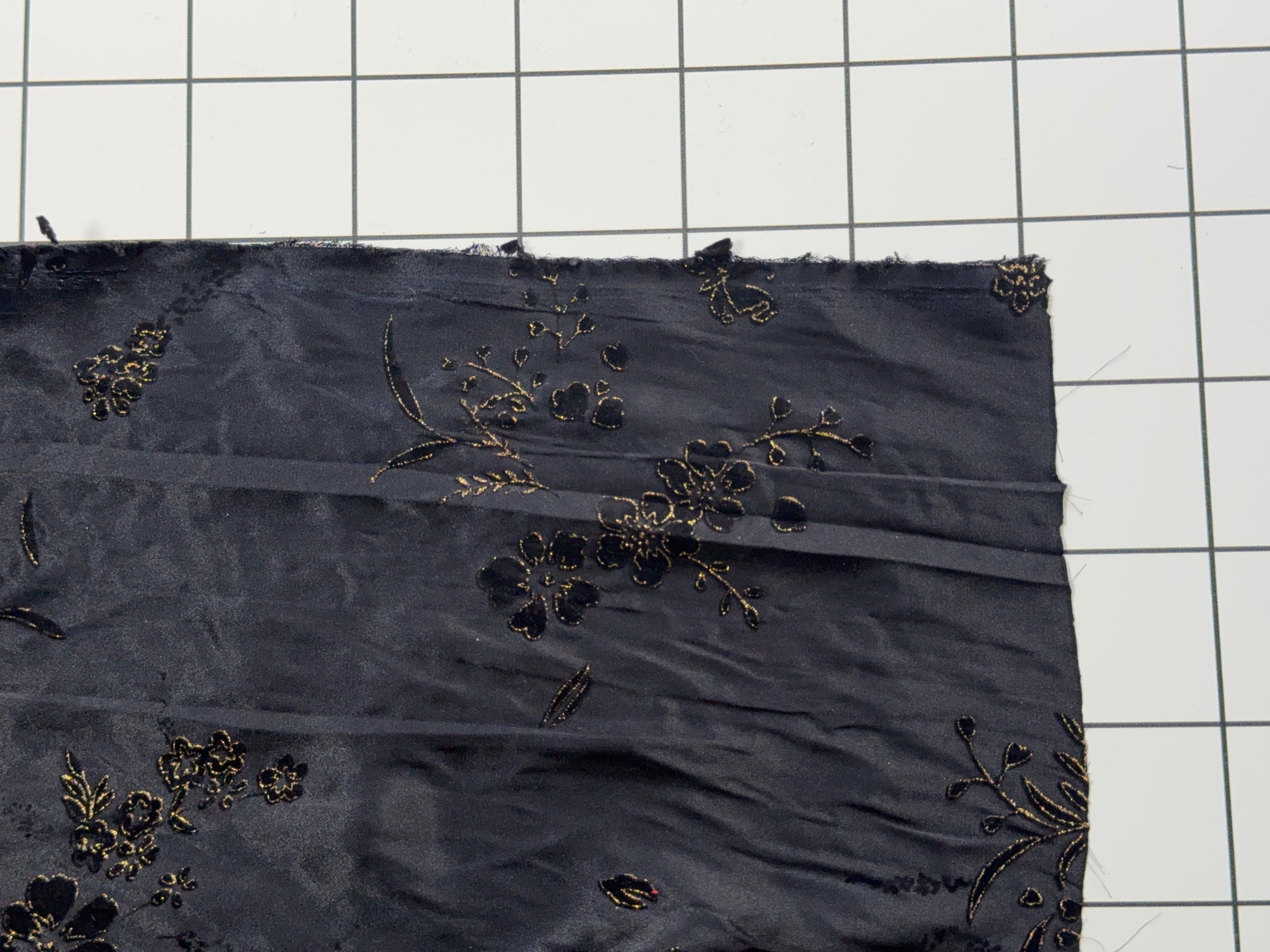 Black fabric with floral embroidery on a grid background