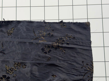 Black fabric with floral embroidery on a grid background