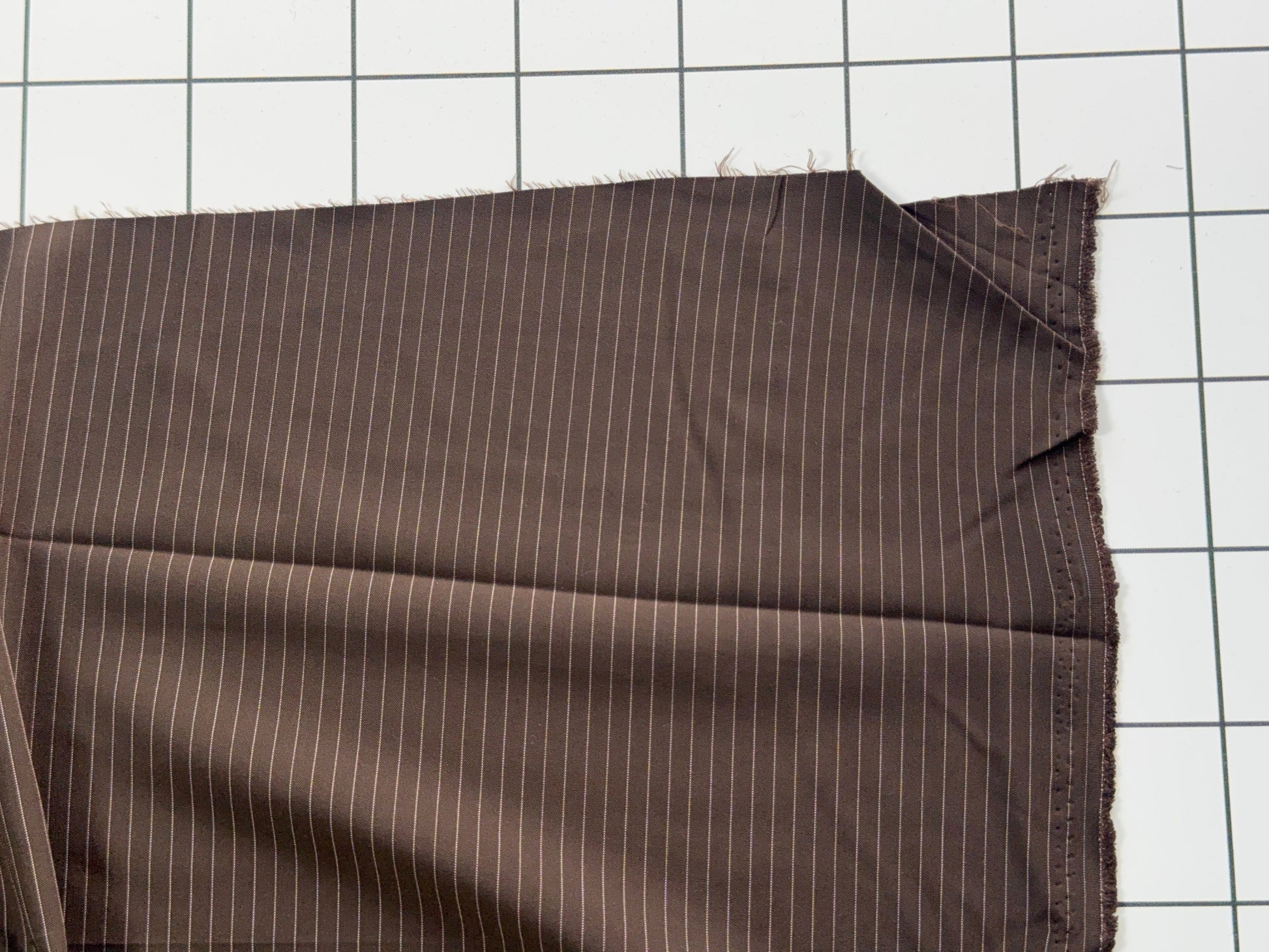 Brown fabric with white pinstripes on a grid background