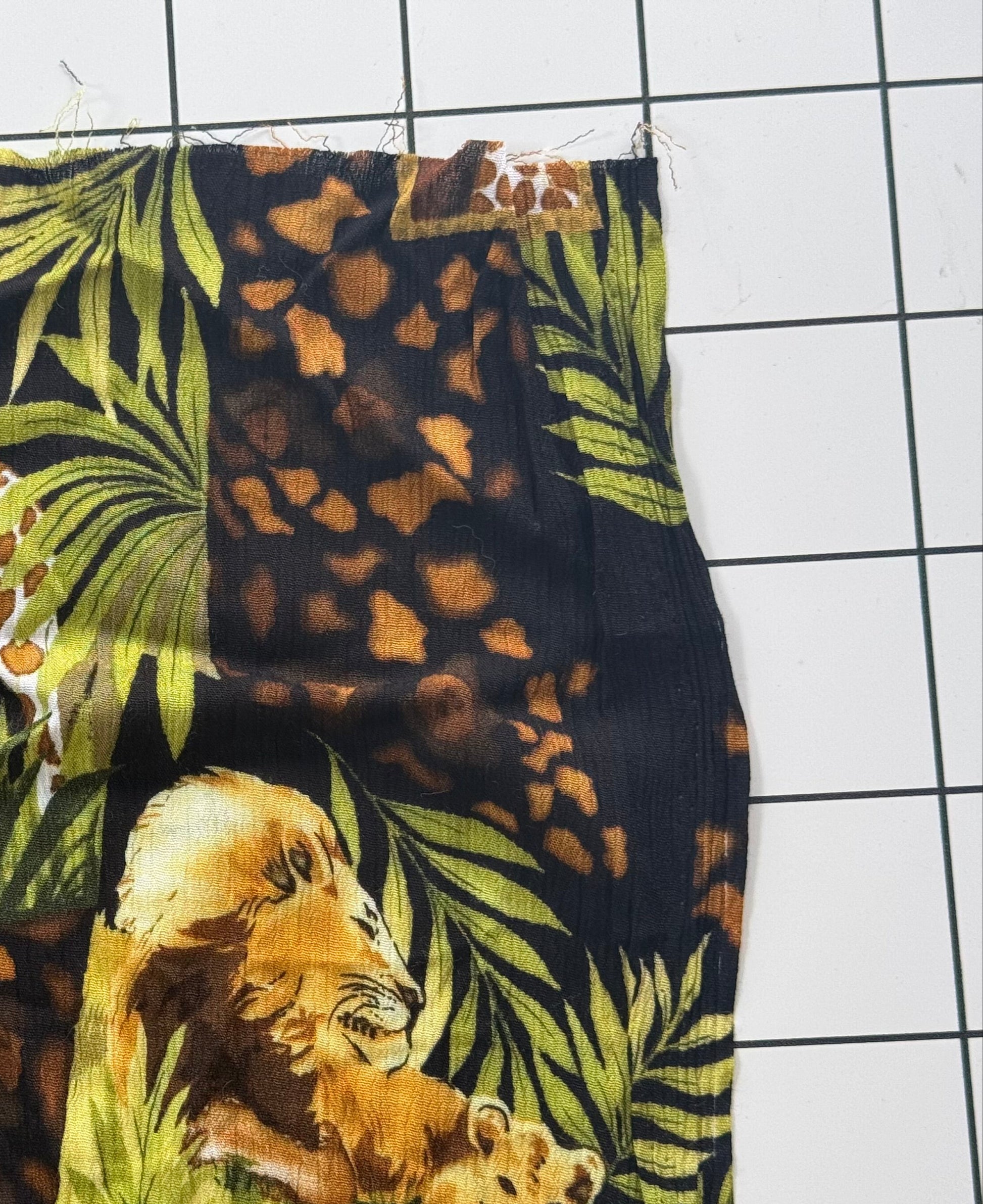 Fabric with jungle-themed design featuring a giraffe, leopards, and tigers on a grid background.