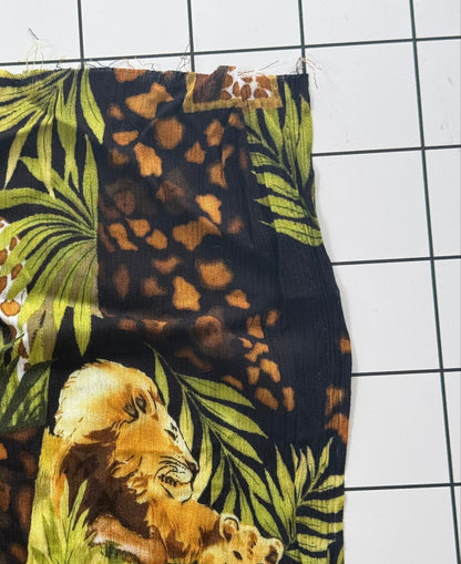 Fabric with jungle-themed design featuring a giraffe, leopards, and tigers on a grid background.