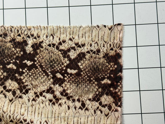 Textile sample with snake skin pattern on a grid background